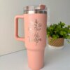 Un termo personalizado jumbo con agarradera de 1200 ml (40 oz) de color rosa con un diseño floral y el nombre Tanya junto a una pequeña planta en maceta.