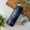 Termo personalizado delgado 590ml 20oz en color azul marino con arte floral y el nombre Mabel, sobre una tabla de madera y plantas verdes—ideal para quienes buscan termos personalizados con un toque elegante.