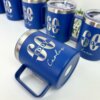 Termo taza personalizado de 360 ml 12 oz en color azul, cada uno etiquetado con 60 EDDY con nombres en letra blanca, dispuestos sobre una superficie blanca con plantas, perfecto para tus bebidas favoritas.