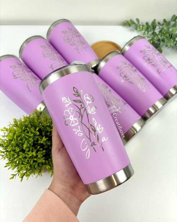 Una mano sostiene un Termo personalizado clásico 590ml 20oz con estampado floral rosa y la palabra "Gala" impresa en él; se ven vasos similares en el fondo.