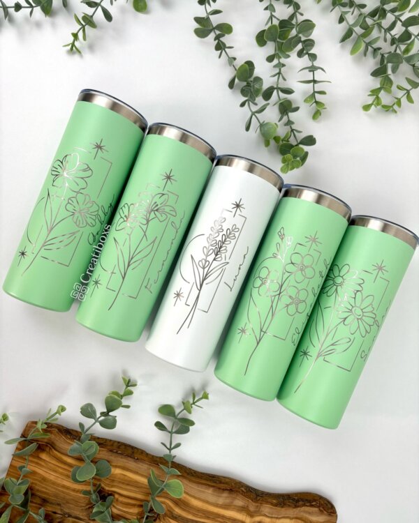 Cinco vasos Termo personalizado delgado de 590 ml 20 oz en tonos pastel con diseños de arte lineal floral, rodeados de hojas verdes sobre una superficie blanca, agregan un toque elegante y personal a su colección de vasos bebidas.