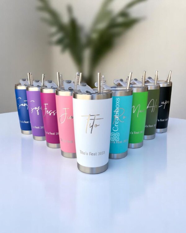 Nueve vibrantes vasos Termo personalizado clásico de 590 ml y 20 oz con nombres y pajitas están dispuestos en fila sobre una mesa blanca, cada uno agregando un toque único, perfecto para cualquier ocasión.