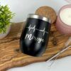 Un Termo Vinero Personalizado negro de 360 ml y 12 oz con tapa plateada se encuentra sobre una tabla de madera, con una línea de latidos de corazón blanca y la palabra Mireya. Cerca hay una vela rosa, una planta pequeña, un posavasos de corcho y una pajita de metal con un cepillo de limpieza.