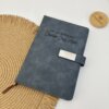 Libreta personalizada A5 con broche magnético plateado, en piel gris, con Lic. en Derecho y Cristian Cruz Ayon grabado en la portada, sobre tapete tejido.
