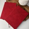 Dos libretas rojas "Libreta personalizada A5 lisa tacto suave" con nombres en relieve en las tapas están colocadas sobre un tablero de madera junto a una suculenta en maceta.