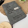 La Libreta personalizada A5 con broche magnético metálico en gris lleva grabadas palabras en español, viene con un bolígrafo, una planta en maceta y una tapa de madera Creatiboxs, todo ello sobre una alfombrilla tejida para una presentación elegante.