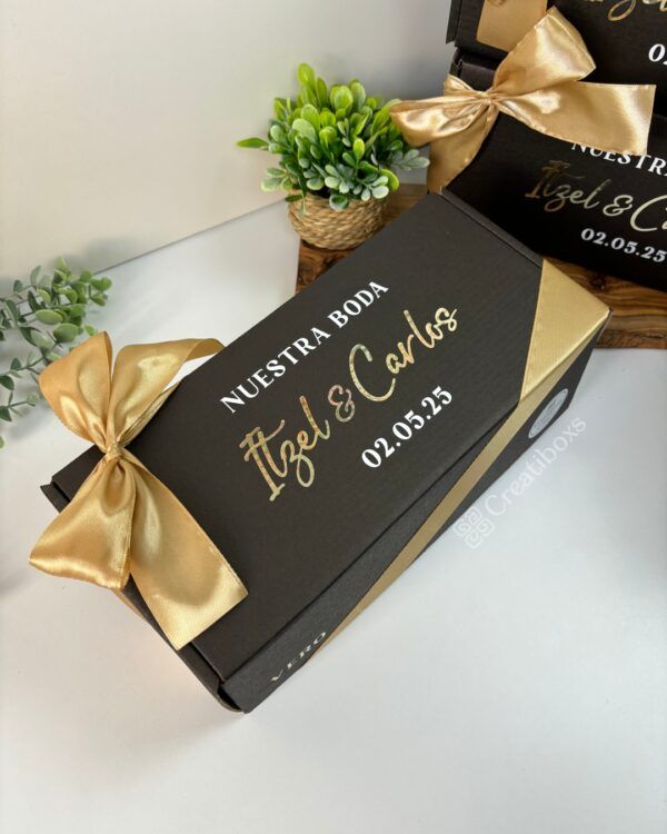 caja negra personalizada de regalo con moño dorado para peticion de padrinos de boda con texto en el exterior nuestra boda nombres y fecha