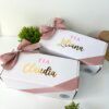 dos cajas chicas color blanco personalizadas para petición de madrinas y moño color rosa