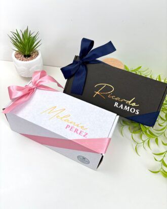 Dos cajas de regalo personalizadas en el exterior con nombre una en color blanco para mujer y otra en color negro para hombre