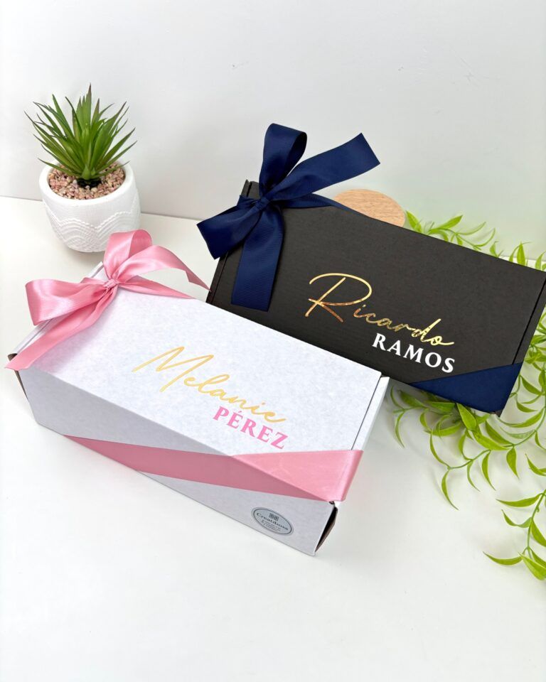 Dos cajas de regalo personalizadas en el exterior con nombre una en color blanco para mujer y otra en color negro para hombre