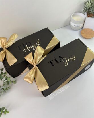 dos cajas color negro personalizadas con texto para padrinos y con moño color champaña