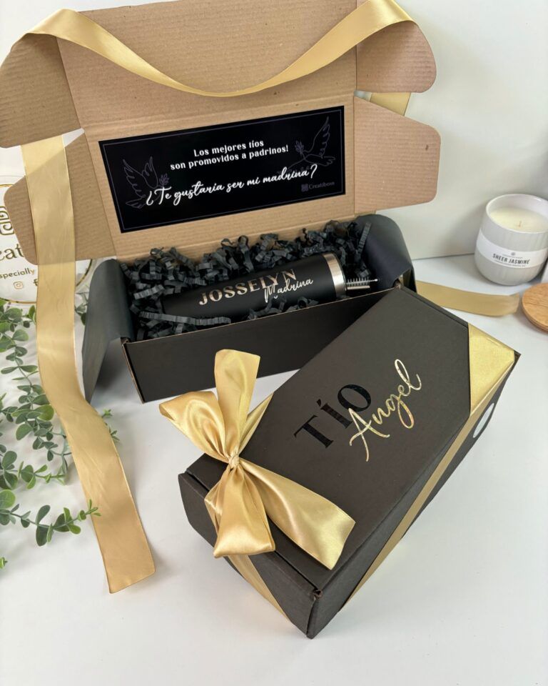 una caja color negro abierta y con mensaje en el interior para realizar peticion de padrinos y tiene como contenido un termo color negro personalizado con laser donde aparece el nombre del padrino y una caja color negro cerrada con moño y texto personalizado tio Angel
