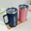 Dos termos de acero donde se aprecia la tapa hermética ambos personalizados en grabado laser uno color rosa para madrina y otro color azul marino para padrino