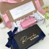 kit de regalo para padrinos una caja abierta con un termo rosa personalizado para madrina y una caja cerrada con nombre de padrino en el exterior