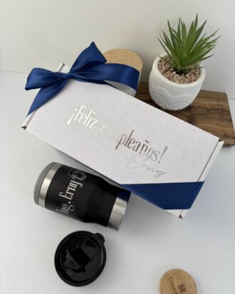 Kit termo portalatas 420ml y caja chica personalizada en color blanco, con texto ¡Feliz cumpleaños!, listón azul, vaso tipo tumbler, planta y tapa de madera sobre una mesa.