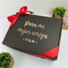 caja personalizada negra con listón rojo y texto dorado "Para mi mejor amiga TQM", decorado con plantas. Perfecta para sorprender a esa persona especial con un regalo único