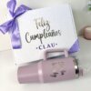 Kit termo jumbo 1200ml y caja mediana personalizada con "Feliz Cumpleaños Clau" y moño morado, junto a vaso rosa.