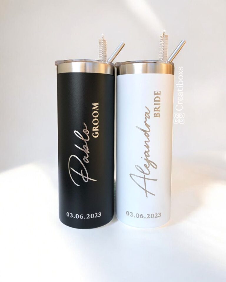 Se muestran dos vasos metálicos: uno negro, con la etiqueta Pablo NOVIO, y otro blanco, con la etiqueta Alejandra NOVIA. Ambos tienen pajitas y están marcados con la fecha 03.06.2023.