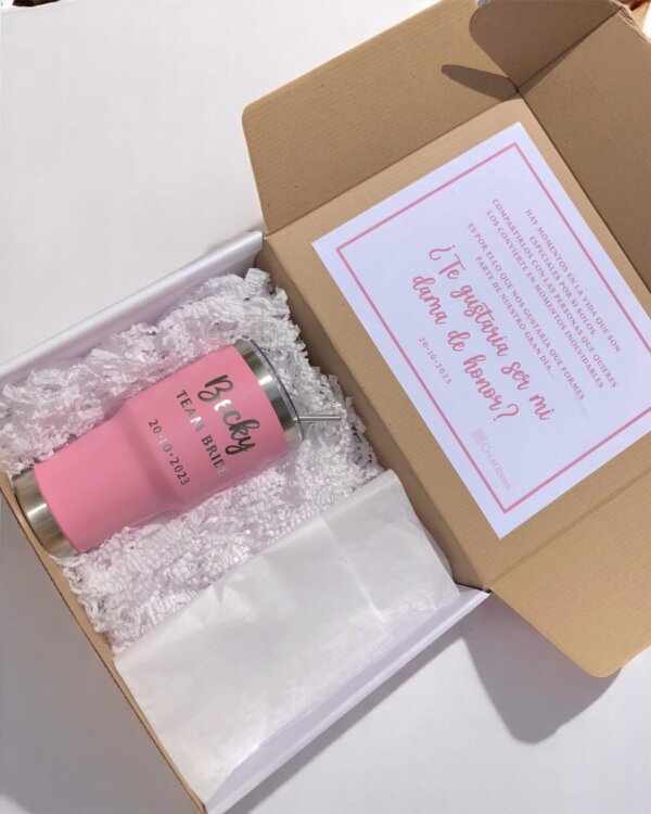 Una caja de regalo con un vaso rosa "Cecy, tea & Bride, 20.01.2023" de nuestros Termos personalizados para boda y una tarjeta de propuesta de boda rosa, perfecta para regalos de boda únicos.