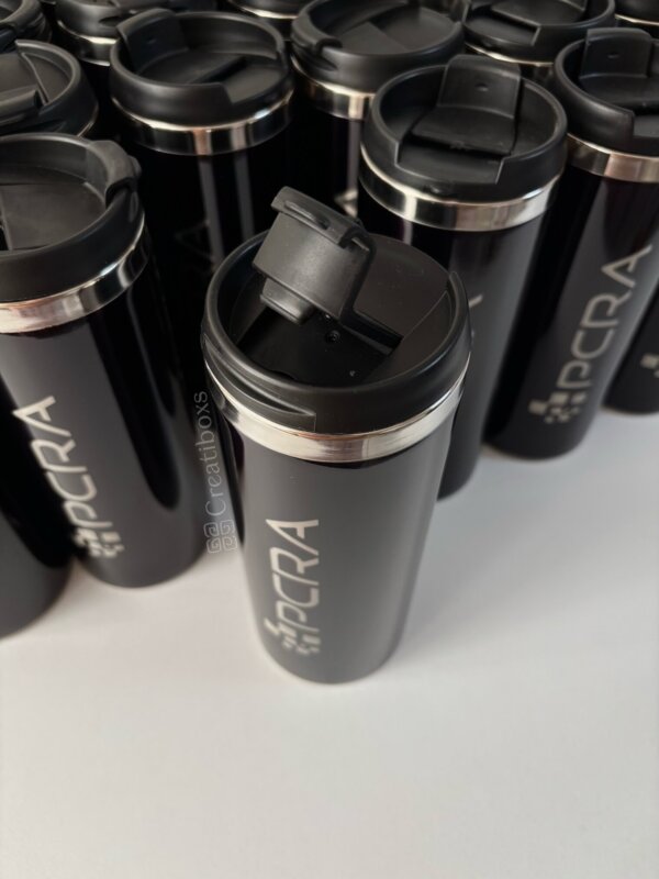 Varios Termos personalizados para regalo corporativo con logo negros, una taza ligeramente hacia adelante y abierta, perfectos para un regalo de empresa destacado.