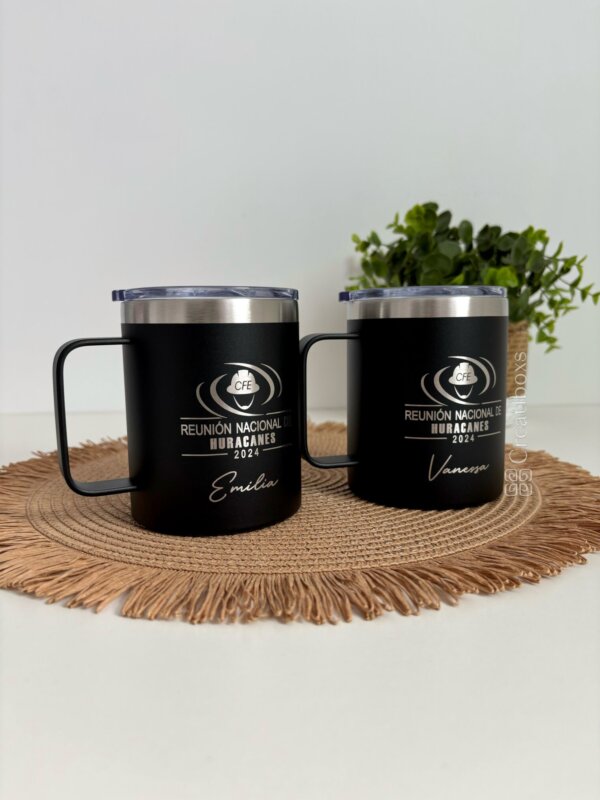 Dos Termos personalizados para regalo corporativo con logo “Reunión Nacional de Huracanes 2024” en negro, sobre tapete tejido y planta de fondo: un elegante obsequio empresarial.