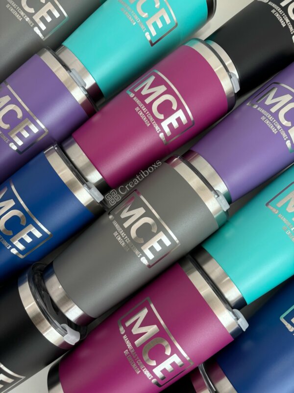 Termos personalizados para regalo corporativo con logo MCE se exhiben en filas diagonales en colores teal, magenta, azul, gris y morado—ideales como regalos empresariales.