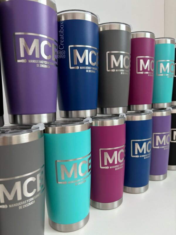 Termos personalizados para regalo corporativo con logo MCE en varios colores están organizados en tres filas sobre un fondo blanco, creando el obsequio ideal para empresas.