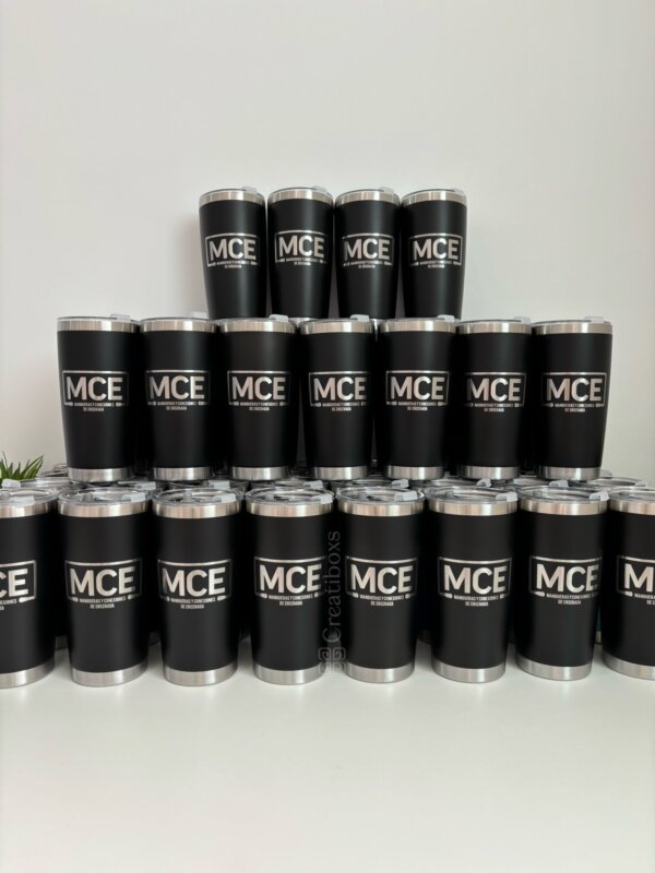 Tres filas de termos personalizados para regalo corporativo con logotipo, cada uno con “MCE” impreso en blanco, apilados en una pirámide contra una pared lisa, ideales para obsequios corporativos.
