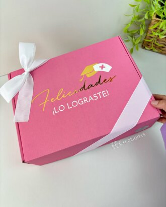 Regalo de graduación con termo personalizado y caja personalizada en rosa con lazo blanco, cofia o gorro de enfermera y texto "Felicidades ¡LO LOGRASTE!"—ideal para celebrar ese gran logro.