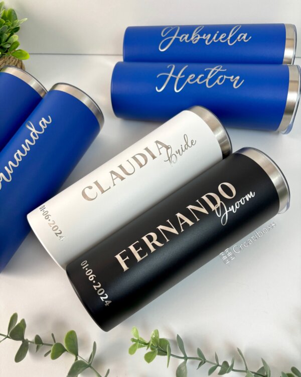 Termos personalizados para boda con nombres, etiquetas de “novia” y “novio”, y la fecha del evento: recuerdos ideales para bodas. Expuestos con elegancia sobre una superficie blanca.