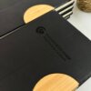 Libretas personalizadas para regalo corporativo con logo, con detalles en madera, apiladas sobre superficie blanca junto a una planta; Perfectas para destacar tu marca o como obsequios empresariales únicos.