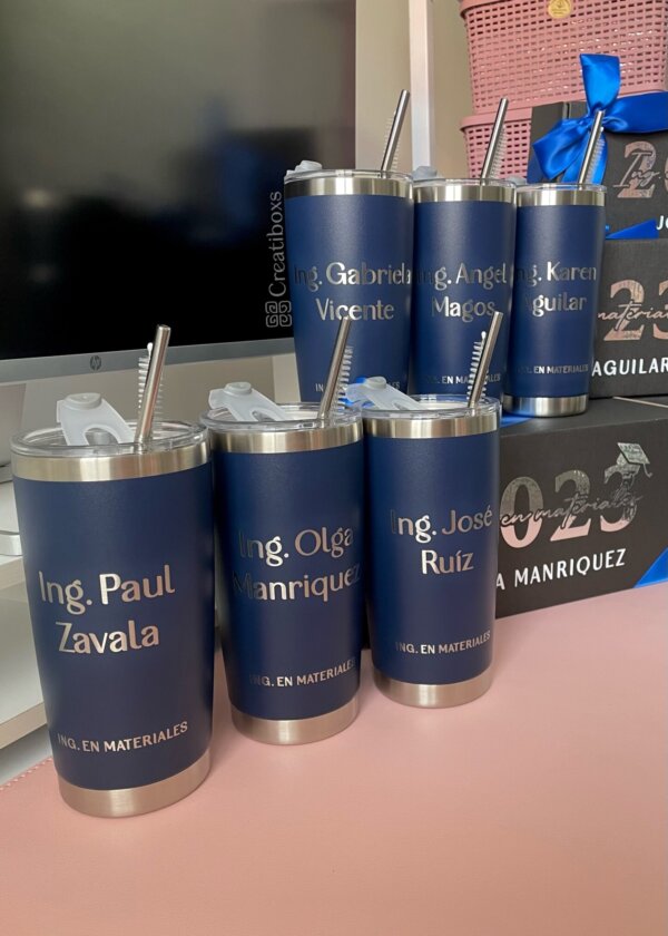 Cinco Regalo de graduación termos personalizados azules con pajillas de metal están sobre un escritorio cerca de un monitor, perfectos para obsequiar.