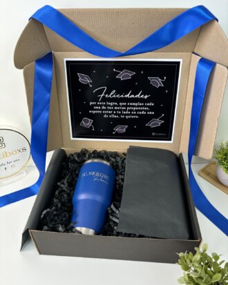 Regalo de graduación con termo personalizado y caja personalizada: incluye termo azul grabado, tarjeta de felicitación en español, lazo azul y papel de relleno negro; el detalle perfecto para celebrar su logro.