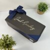 Kit termo clásico grande 890ml y caja chica personalizada en color negro con listón azul marino y el nombre Joel Sanchez en la tapa, rodeado de pequeñas macetas.
