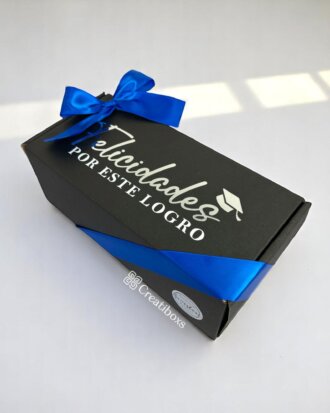 Regalo de graduación termos personalizados: elegante caja negra con lazo azul, mensaje "Felicidades por este logro" y dibujo de birrete. Ideal para obsequiar termos personalizados a graduados.