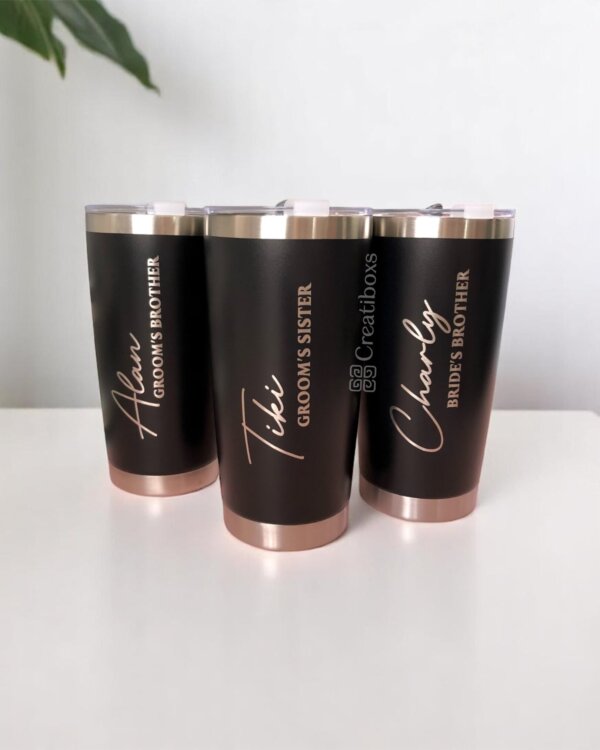Se muestran sobre una superficie blanca tres "Termos personalizados para boda" en color negro y oro rosa, etiquetados para los miembros de la fiesta de bodas.