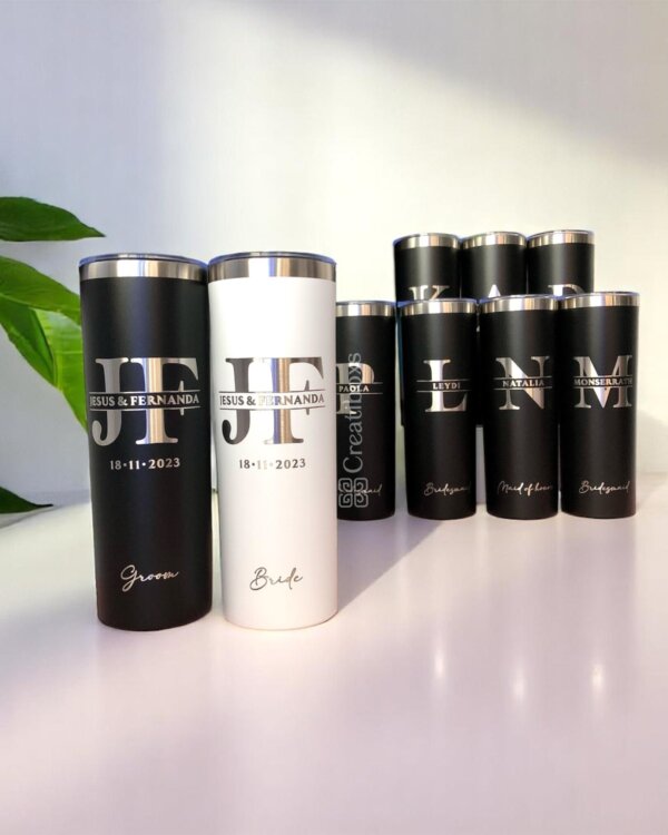 Termos personalizados para boda en blanco y negro, etiquetados y exhibidos sobre una superficie blanca con una planta verde.