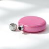 A su lado, sobre una superficie blanca, hay una Licorera personalizada de acero inoxidable 148ml 5oz, redonda y de purpurina rosa, con un tapón joya.