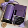 Kit regalo corporativo: termo clásico 590ml, libreta y bolígrafo personalizado con tarjeta, todo en caja de madera con listón morado. Ideal para impresionar y destacar en cualquier ocasión.