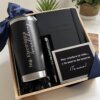 Kit regalo corporativo con termo clásico 590ml, libreta y bolígrafo personalizado con tarjeta, acompañado de dos plantas en maceta al fondo.