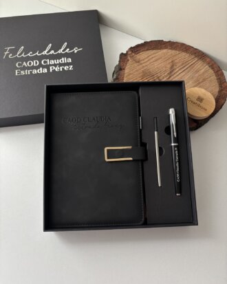 Caja de regalo con un Set libreta con broche magnético contorno metálico y bolígrafo en caja, etiquetado personalizado CAOD Claudia Estrada Pérez en la portada, además de un elegante bolígrafo y lápiz.