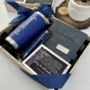 Kit regalo corporativo: termo clásico 590ml, libreta con broche magnético y bolígrafo personalizado, incluye tarjeta de agradecimiento y se presenta con cinta azul, ideal para regalar junto a una planta.