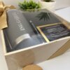 Kit regalo corporativo con termo clásico 590ml, libreta y bolígrafo personalizado con tarjeta, presentados en elegante caja junto a plantas en maceta sobre superficie blanca.