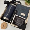 Elegant Kit regalo corporativo termo clásico 590ml, libreta broche magnético y bolígrafo personalizado con tarjeta, todos presentados elegantemente con lazo negro y una pequeña planta.