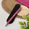 Un bolígrafo personalizado mate con acabado soft touch y detalles plateados, personalizado para Profe Tania, descansa sobre un estuche negro junto a una libreta y un portavasos redondo de madera.