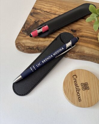 Bolígrafo personalizado mate con acabado soft touch y detalles plateados, grabado con LIC. BRENDA MEDINA, presentado en estuche negro junto a un portalápices y una tapa de madera.