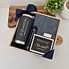 Kit regalo corporativo: termo clásico 590ml, libreta con broche magnético, bolígrafo personalizado y tarjeta, todos en negro elegante y lazos azul marino.