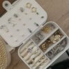 Joyero personalizado de cuero sintético chico con compartimentos organiza aretes, anillos y pulseras sobre una superficie de madera.