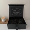 Elegante Caja personalizada con 2 diseños rígida magnética en color negro, con un mensaje de felicitación en su interior, expuesta junto a una vela sobre una superficie blanca.