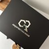 Caja personalizada con 2 diseños, rígida y magnética, con logo sobre una superficie blanca junto a una tabla de madera.